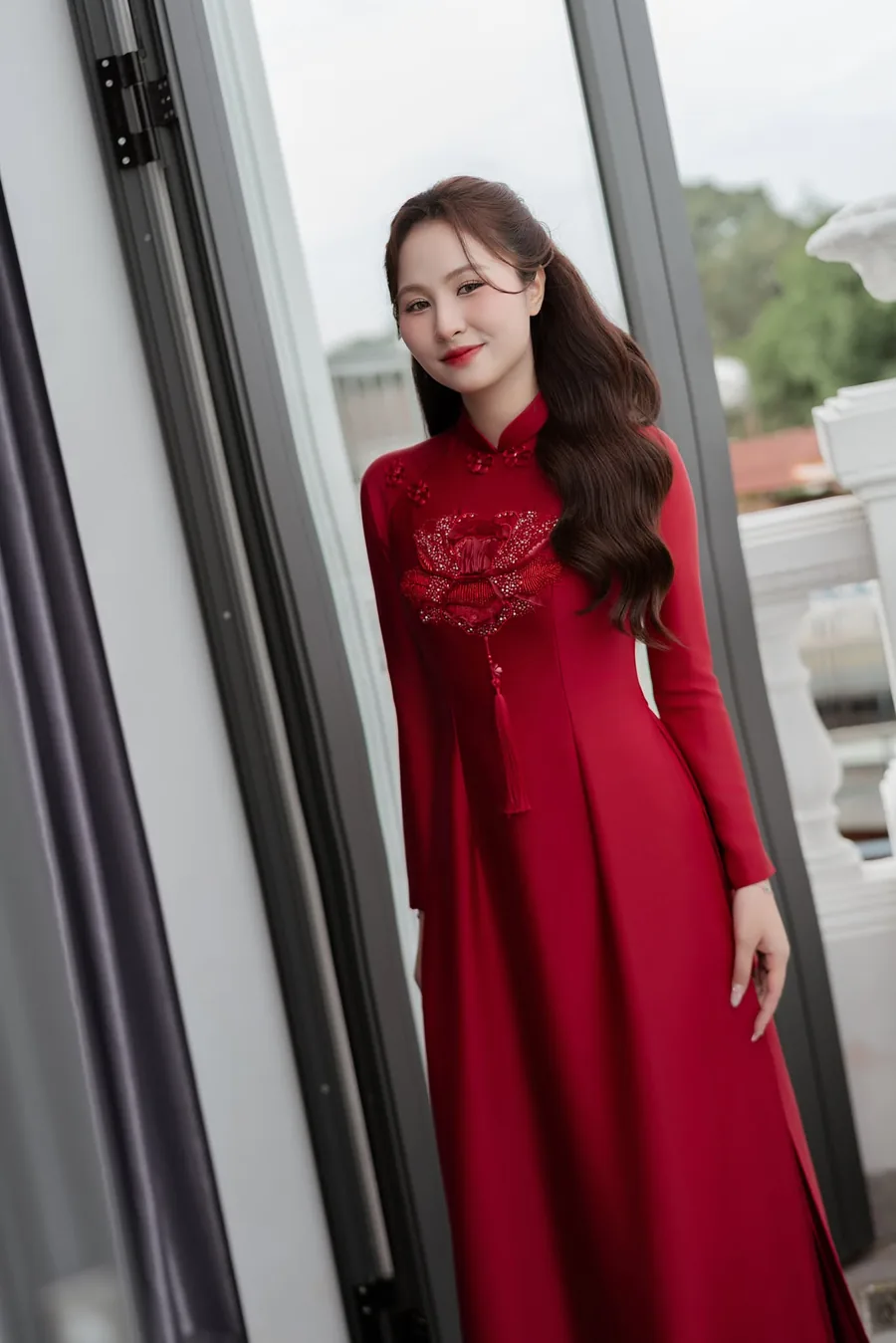 Cô dâu áo dài đỏ thêu hoa bên khung cửa sổ